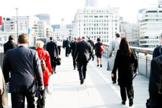 Several people walking across a bridge in business attire.