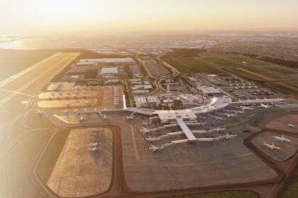 Aerial view of an airport terminal with multiple aircraft parked at gates and on surrounding tarmacs.