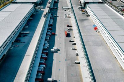 Aerial view of trucks outside giant logistics warehouse transit centre.