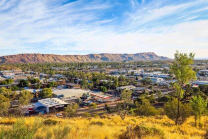 Elevated view over an Australian regional town, with buildings and trees beneath a prominent rocky mountain range.