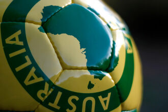 Close-up of a green and gold football featuring a map of Australia.