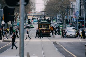 A busy Melbourne CBD street with pedestrians, traffic and a City Circle tram.