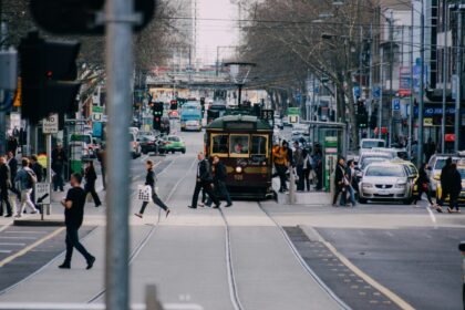 A busy Melbourne CBD street with pedestrians, traffic and a City Circle tram.