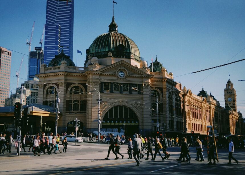 People crossing the road outside busy Flinders Street Station, Melbourne.