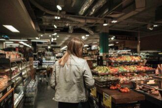 A woman browses the fruit and vegetable isle at the supermarket.