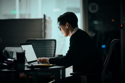 A man sits at his desk using a laptop.